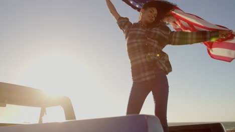 Frau-Schwenkt-Amerikanische-Flagge-Auf-Pickup-Truck-Am-Strand-4k