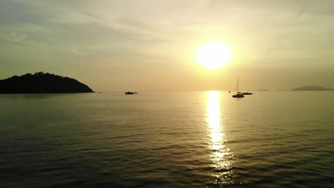 Low-flight-over-the-ocean-with-golden-sunset-and-boats-on-the-background