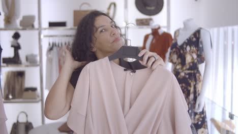 una clienta pensativa con vestido, mirándose a sí misma en un espejo