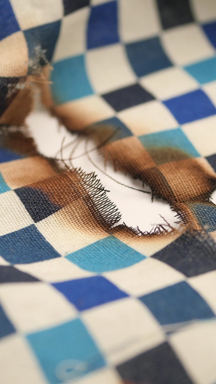 Close-up of a Burnt Hole in Blue and White Checkered Fabric