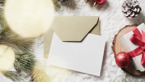 video of christmas decorations and white card with copy space on snow background