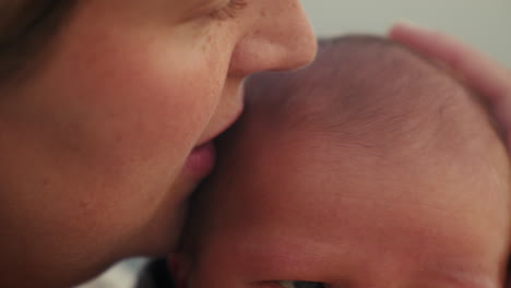 tender moment of mother kissing newborn baby's head