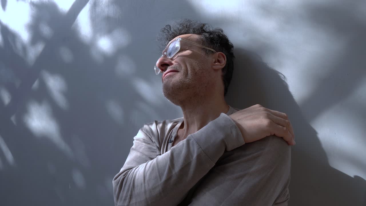 un hombre de cuarenta o cincuenta años parece preocupado, abrazándose en un gesto de preocupación