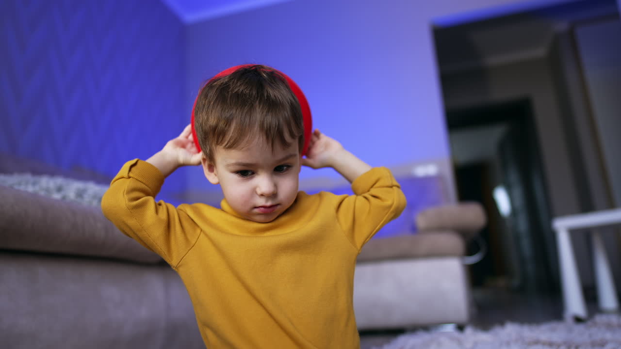 Cute toddler with brown hair wearing yellow sweater. Little boy holding a red ring from pyramid behind his head. Low angle view.