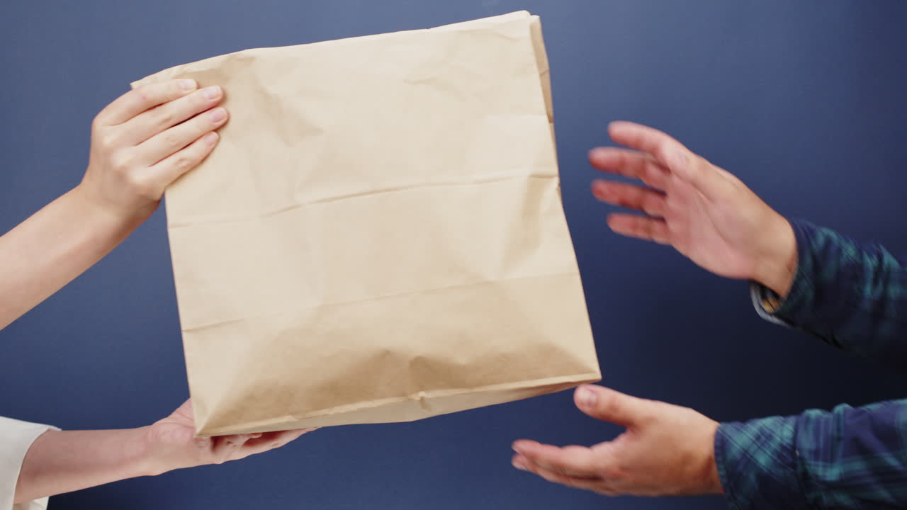 Hands Exchanging a Brown Paper Bag