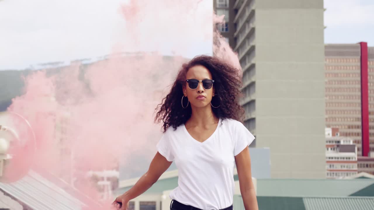 Fashionable young woman on urban rooftop using a smoke grenade