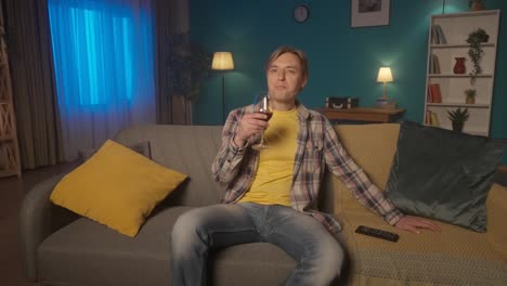 Man Relaxing on Sofa, Drinking Wine and Watching TV