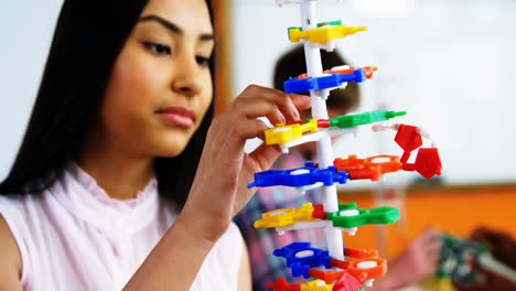 Schoolgirl-experimenting-molecule-model-in-laboratory-at-school