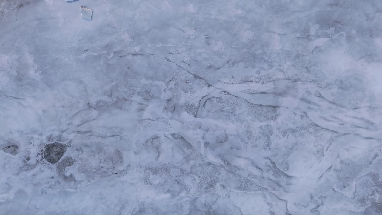 Aerial view of frozen sea ice, capturing abstract patterns and textures from above in a dramatic natural landscape