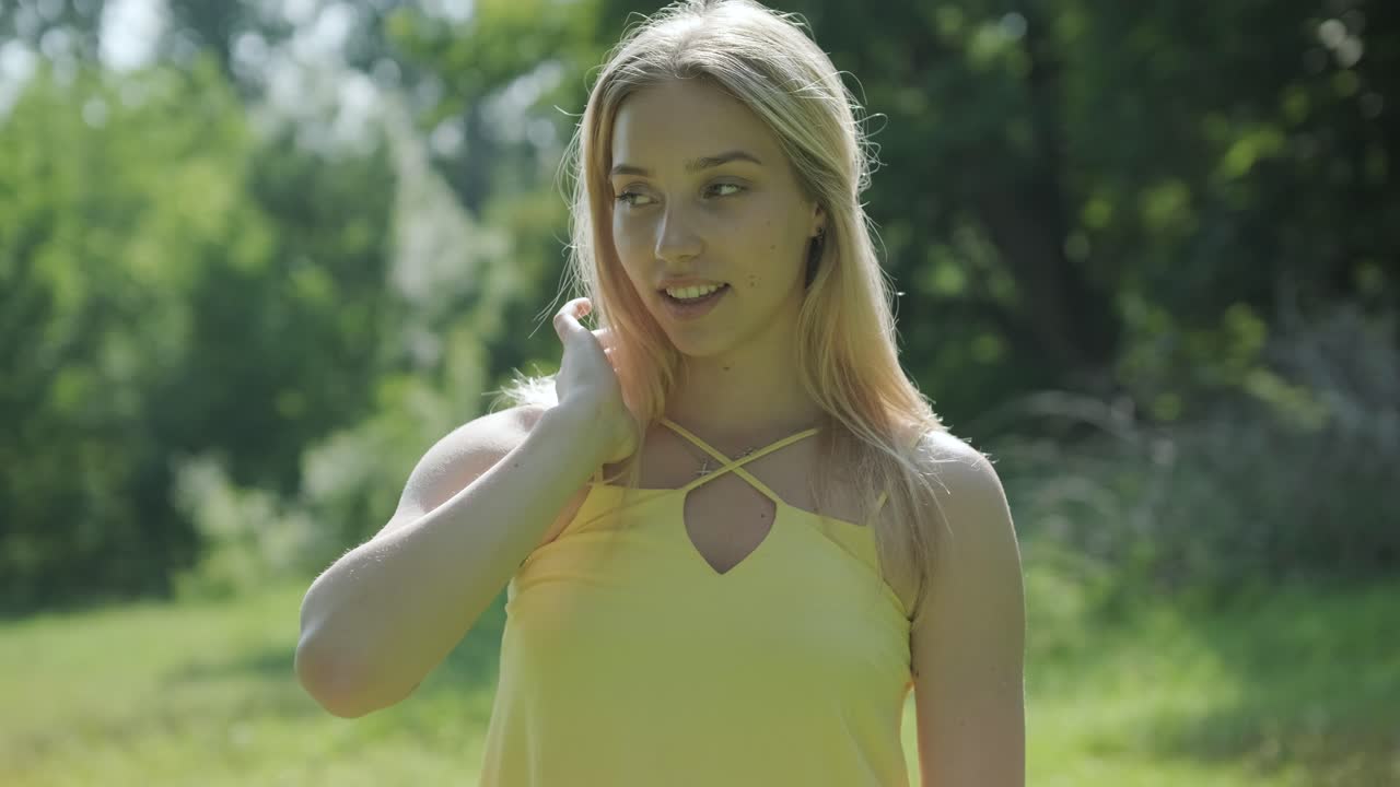 아름다운 젊은 소녀가 자유의 춤을 추고 있습니다. 여름 공원에서 뒷면에 나무가 있습니다.