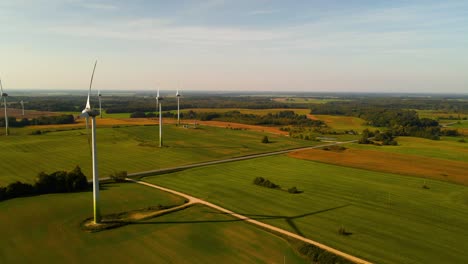 Toma-De-Drones-De-Las-Turbinas-Eólicas-Que-Funcionan-En-Un-Parque-Eólico-Que-Genera-Energía-Eléctrica-Verde-En-Un-Amplio-Campo-Verde-En-Un-Día-Soleado,-Uso-De-Recursos-Renovables-De-Energía,-Diapositiva-Hacia-La-Izquierda