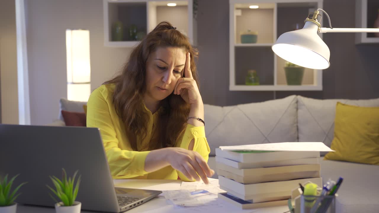 la ama de casa pensativa mira las facturas y los papeles de deuda.