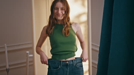 Slim figure trying old jeans closeup. Happy joyful girl dancing enjoying weight