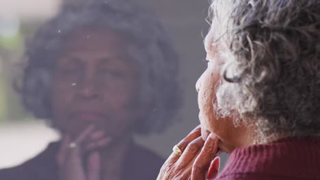 thoughtful senior african american woman looking through window