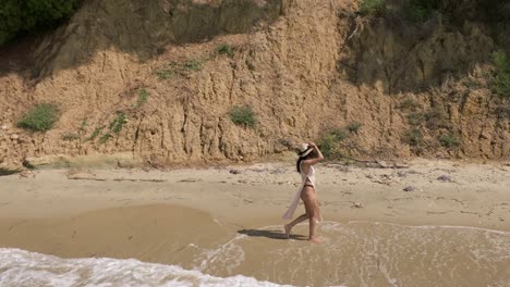 gorgeous woman in swimsuit walking barefoot on sandy shore by the beach in kassandra, greece