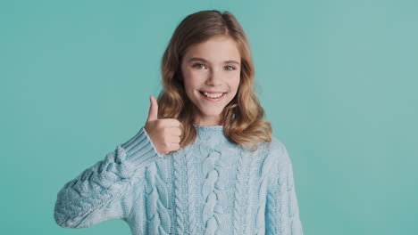 teenage caucasian girl with thumbs up looking at the camera.