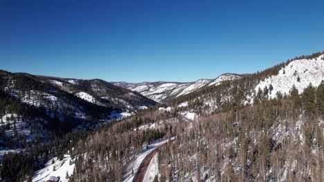 aerial drone shot over a remote highway that bends around a mountain range