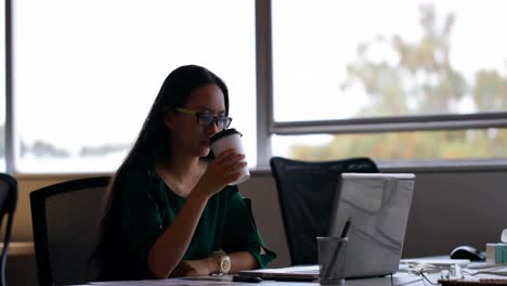 Female-executive-using-laptop-at-desk-in-office-4k