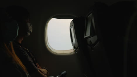 Man-with-COVID-mask-in-dark-airplane-looking-out-the-window