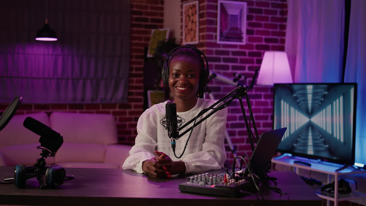 Portrait of african american podcaster sitting at desk in home recording studio with boom arm microphone