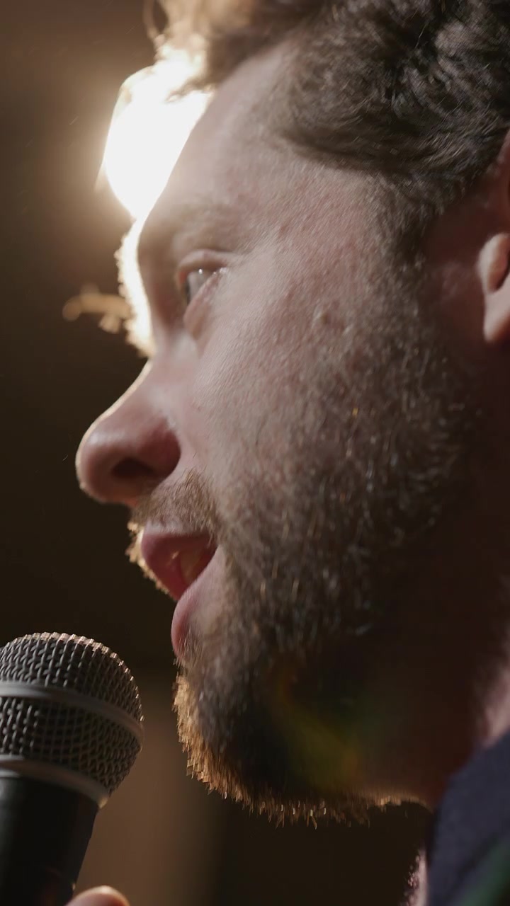 Primo piano di un comico di stand-up che parla al microfono sotto le luci del palco