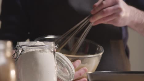 close up of man in kitchen at home whisking ingredients to bowl to bake cake 2