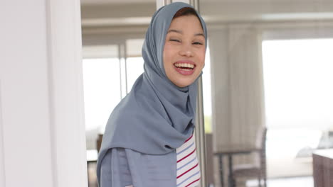 portrait of smiling biracial woman in hijab at home with copy space, slow motion