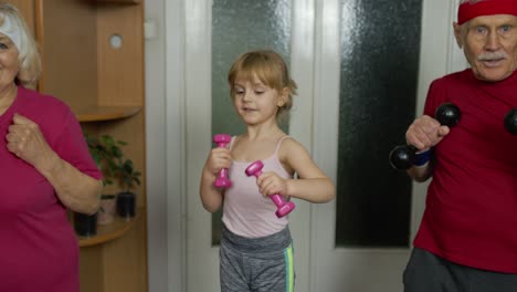 Active-senior-couple-grandmother-grandfather-with-child-kid-girl-doing-fitness-dumbbells-exercises