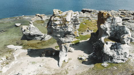 Aerial-moving-away-and-around-birds-eye-drone-view-of-calm-Baltic-sea-and-interesting-rock-formation-in-coastline-of-Gotland-island