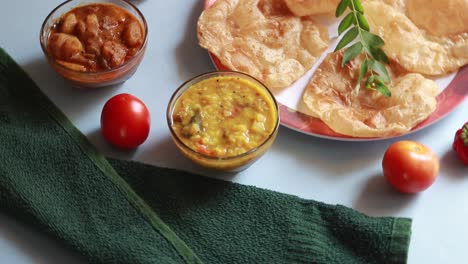 rotation chole bhature or chick pea curry and fried puri served in terracotta crockery over blue background