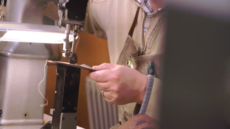 bespoke shoemaker stitching together leather pieces for shoe