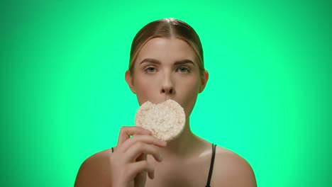 Portrait-young-woman-eats-a-delicious-white-rice-cake,-isolated-green-background