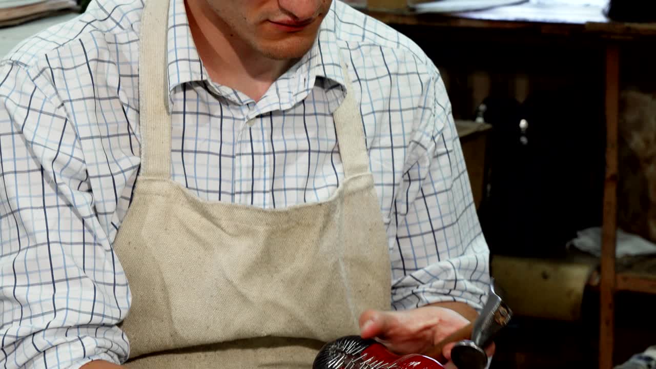 zapatero feliz sonriendo a la cámara, mientras hace zapatos