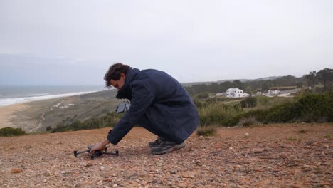 a young man taking off a drone at a scenic location in portugal