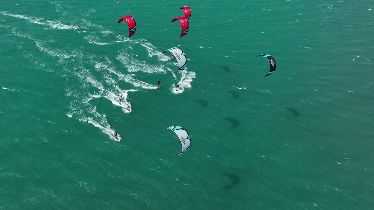 브라질 북부 밝은 녹색 바다에서 강풍 속에서 바다를 가로질러 경주하는 카이트서퍼 그룹의 넓은 공중 샷
