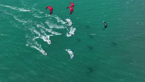 wide aerial shot of a group of kitesurfers racing across the ocean in the high wind on light green sea, northern brazil