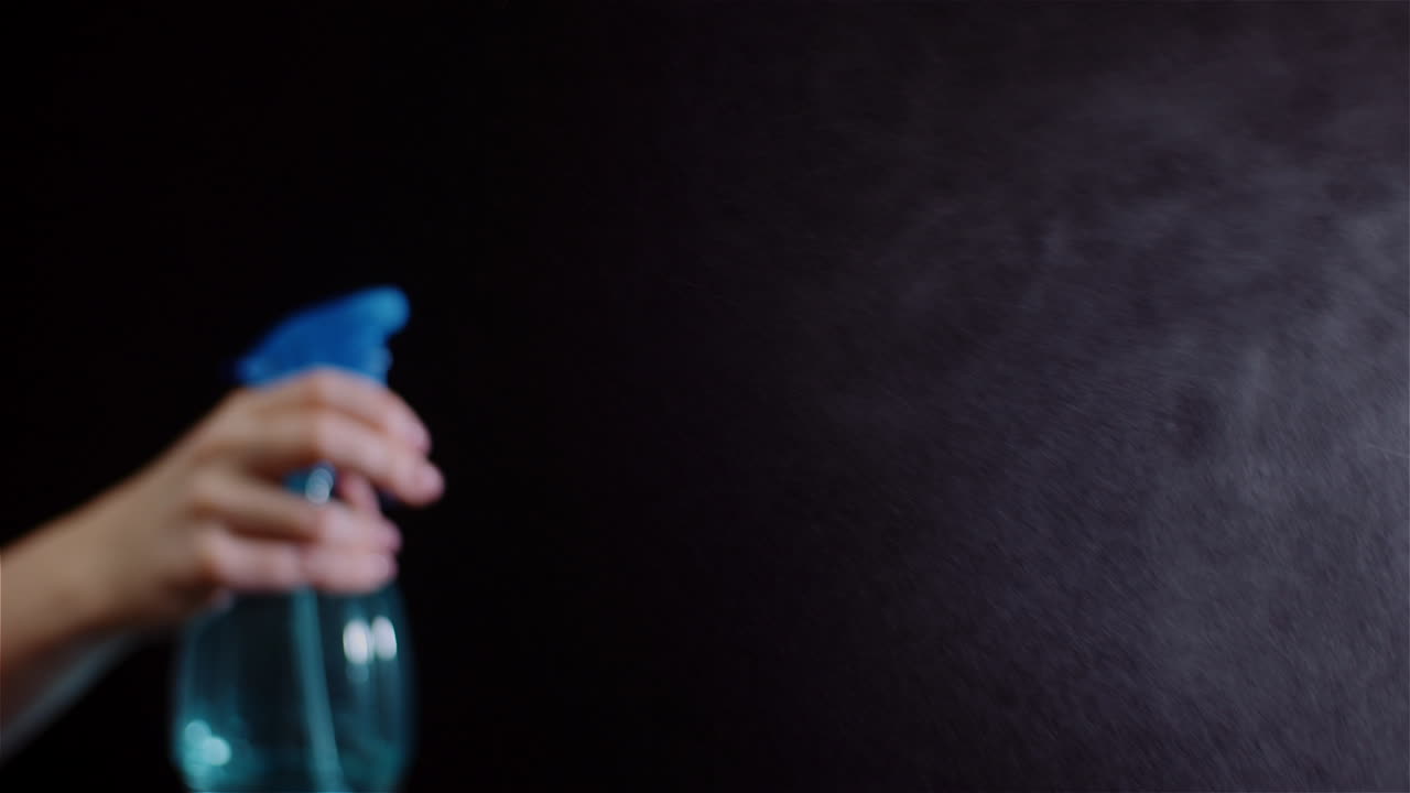 스프링클러를 사용하여 손을 닫고 검정색 배경 2에 물을 뿌립니다.