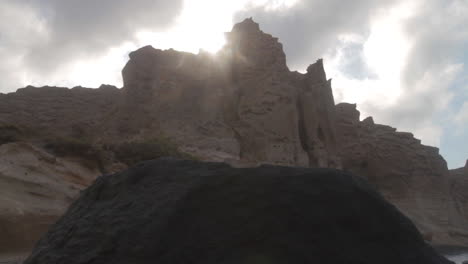 tracking shot of white volcanic cliffs at a black sand beach on the island of santorini, greece