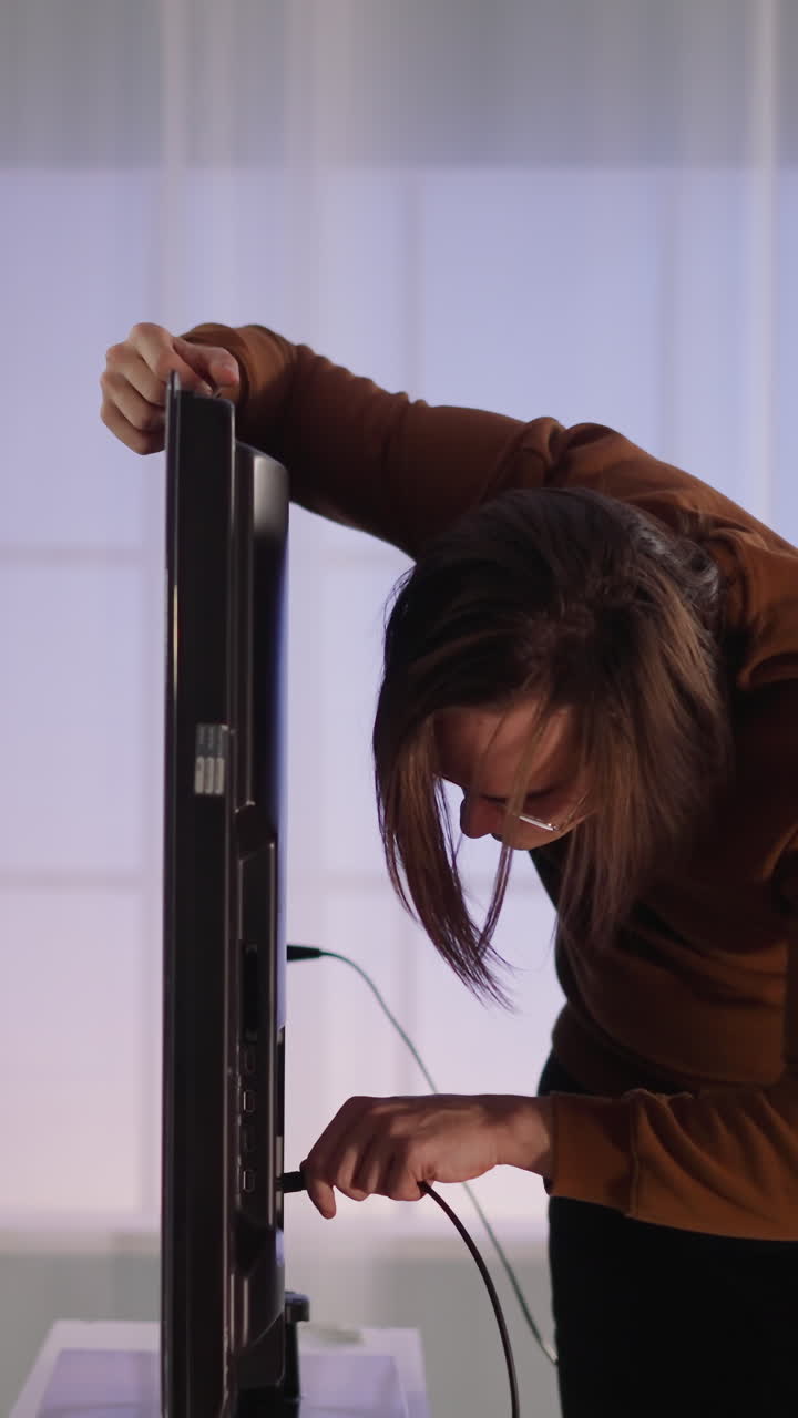 hombre concentrado con gafas enchufa el cable a la televisión inteligente en un gran apartamento en cámara lenta. hombre hipster ensambla dispositivo para ver contenido de video en casa