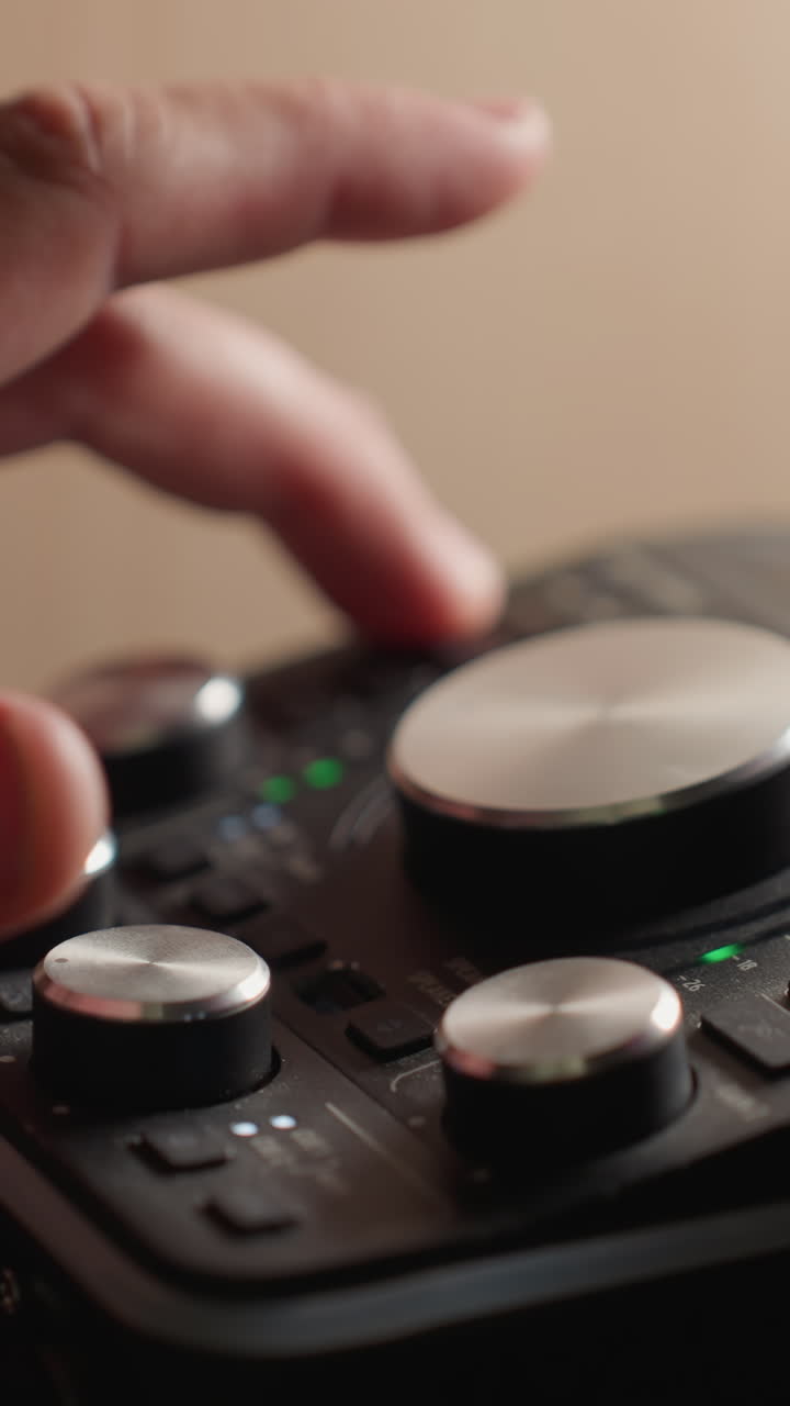 Close-up of a hand carefully adjusting the knobs on a sound mixer to fine-tune audio levels. with the sound mixer s controls and indicators clearly visible