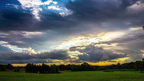 Sich-Bewegende-Wolken-Am-Blauen-Himmel-Und-Lichtstrahlen,-Die-über-Ein-Wunderschönes-Grünes-Feld-Kreuzen