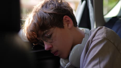 young student resting on car seat listening to music