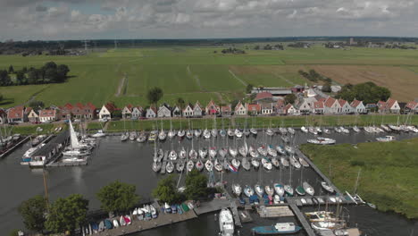 aerial backing up showing the small village durgerdam near amsterdam with its recreational port area with many sailboats docked against an overcast sky