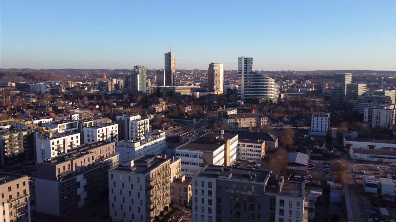 Flugaufnahme im Vorbeiflug in Richtung der Innenstadt von Vilnius mit Wolkenkratzern in der Ferne.