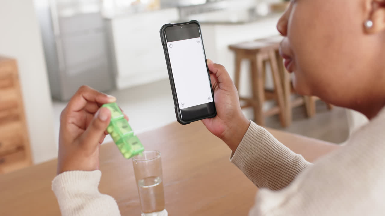 슬로우 모션으로 약을  ⁇ 고 있는 아프리카계 미국인 여성이 스마트폰을 사용하여 복사 공간을 가지고 있습니다.