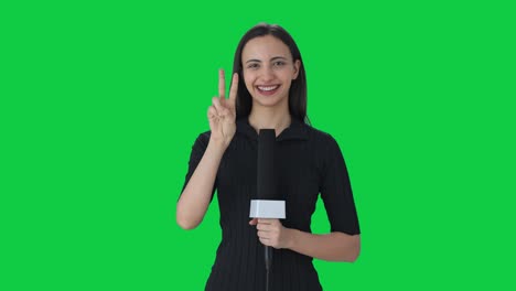 feliz reportera de noticias india mostrando el signo de la victoria pantalla verde