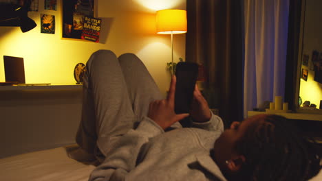 teenage girl relaxing on bed using smartphone at night