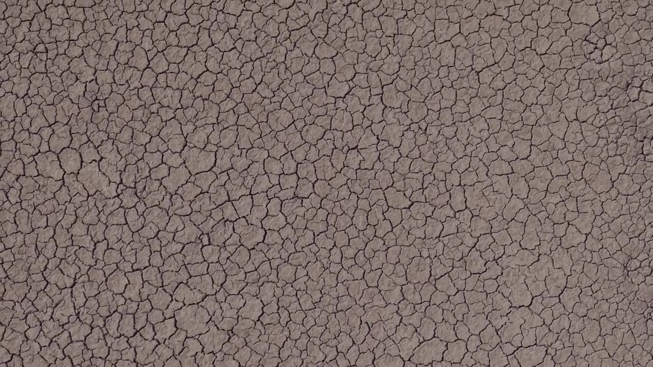 広範囲にひび割れた乾燥した大地のクローズアップが、フレーム全体に詳細な自然のテクスチャを作り出している