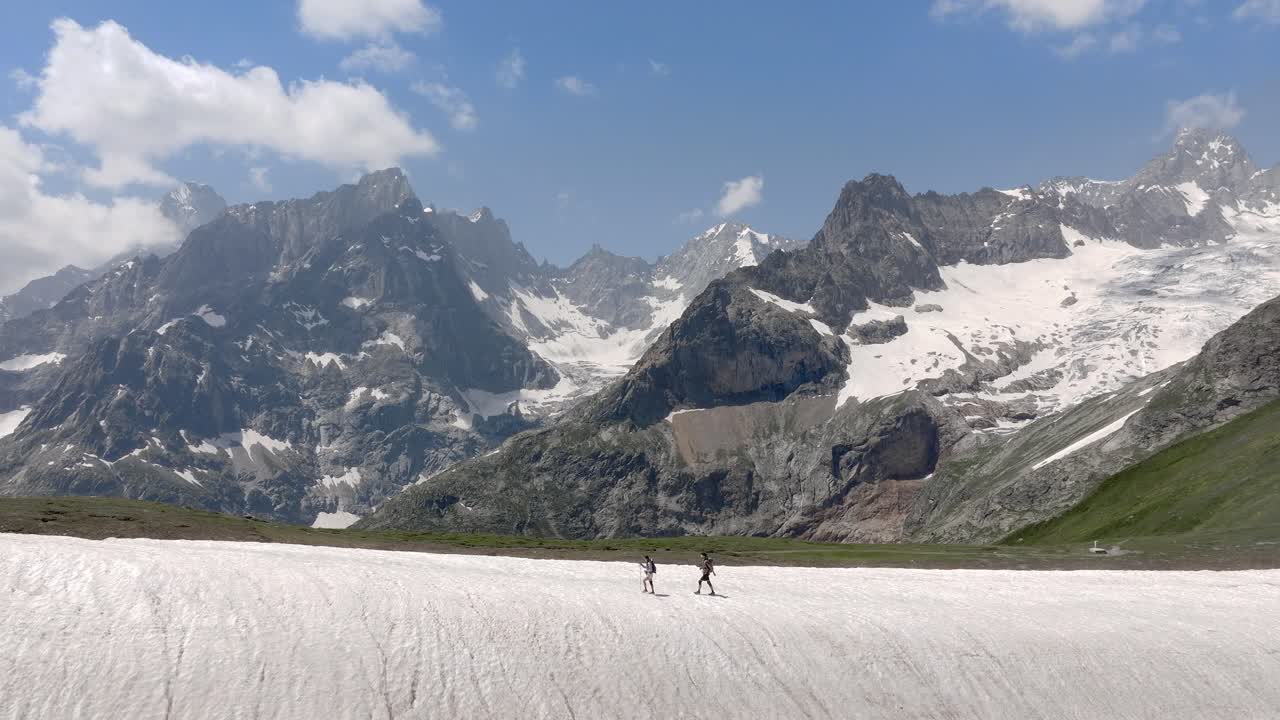 Snow-covered peaks and scenic alpine trails characterize this beautiful hike in the Mont Blanc region, couple hikes on snow ridge, aerial