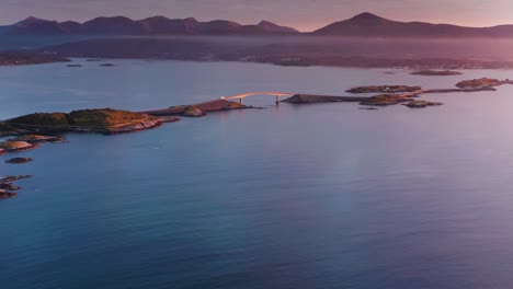 a beautiful view of a bridge spanning between islands on the atlantic road bathed in the warm hues of a setting sun.